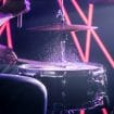 The Man Plays The Drums, On The Background Of Colored Lights