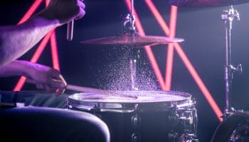 The Man Plays The Drums, On The Background Of Colored Lights