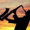 jazzman qui joue du saxo au coucher du soleil