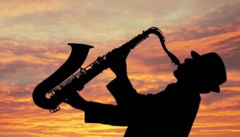 jazzman qui joue du saxo au coucher du soleil